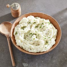 mashed potatoes in a bowl with a wooden spoon and salt shaker on the side