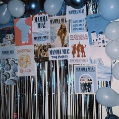 a bunch of balloons are hanging on the wall in front of a party banner and some posters