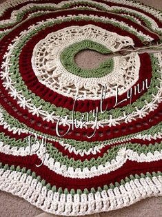 a crocheted afghan with scissors on top of it and the yarn is red, white and green