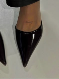 a woman's feet with tattoos on her ankles and heels in front of a white wall