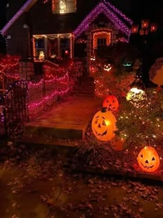 pumpkins lit up in front of a house with purple and red lights on them