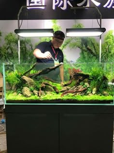 a man standing in front of an aquarium filled with plants