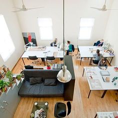 an overhead view of people sitting at desks in a large room with lots of windows