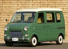 an old green van parked in front of a brick wall