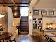 a living room filled with furniture and a fire place next to a staircase leading up to the second floor