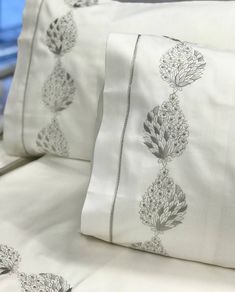 two white pillows sitting next to each other on a bed