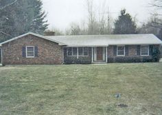 a brick house sitting on top of a lush green field