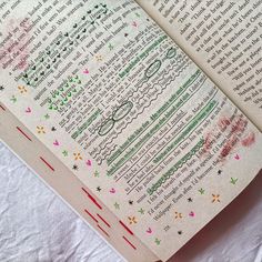 an open book with writing on it sitting on top of a white sheeted surface