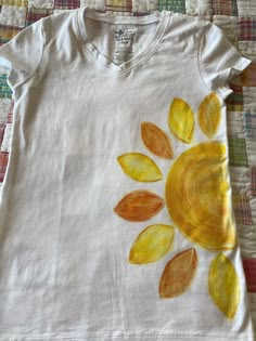 a white shirt with yellow leaves painted on it