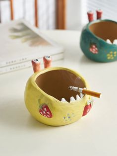 two ceramic bowls with toothbrushes in them on a table next to each other