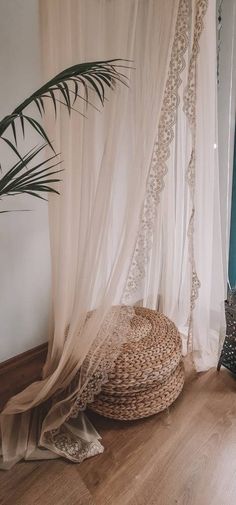 a wicker basket sitting on the floor in front of a window with sheer curtains