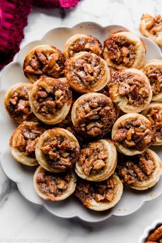 a white plate topped with mini pecan pies on top of a marble counter