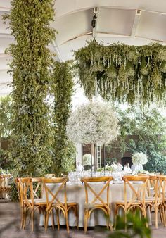 an outdoor dining area with tables and chairs covered in greenery hanging from the ceiling