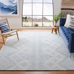 a living room with a blue couch, chair and rug in front of a large window