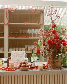 a table topped with lots of red flowers next to wine bottles and glasses filled with liquid