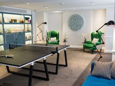 a ping pong table in the middle of a room with green chairs and shelves