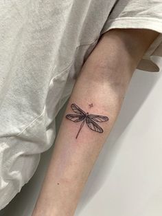 a small dragonfly tattoo on the arm