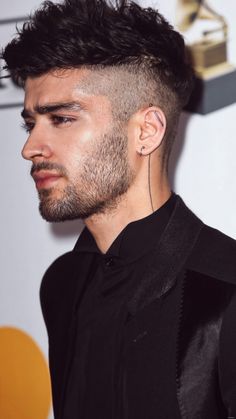 a close up of a person with a haircut and piercings on his ear