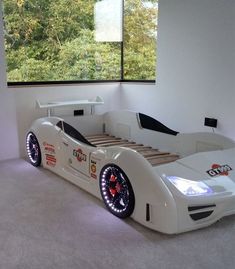 a bed made to look like a race car in a room with large windows and white carpeting