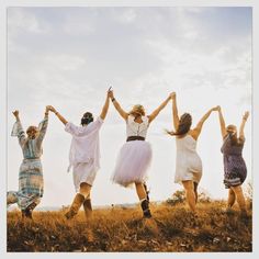 four women are jumping in the air with their hands up and one woman is wearing a white dress