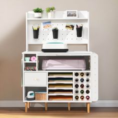 a white desk with lots of drawers on top of it and some plants in pots