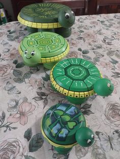 three turtles painted on top of each other sitting on a table with flowered cloth