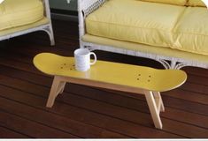 a yellow skateboard sitting on top of a wooden table next to a white couch