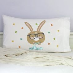 a bed with a pillow that has an image of a bunny wearing glasses on it