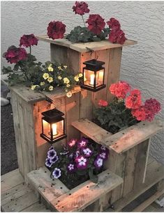 some flowers are sitting in wooden boxes with lights on them