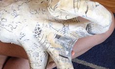 a person is holding an animal made out of newspaper paper with writing all over it