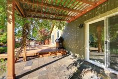 an outdoor covered patio area with sliding glass doors and wooden pergolated roofing