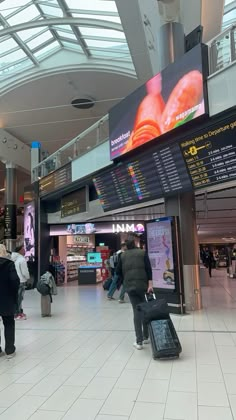 people are walking through an airport with their luggage and check - in counters on the floor