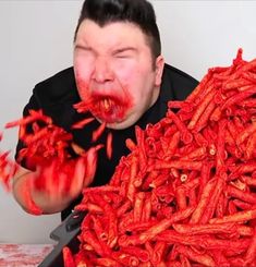 a man with red paint on his face and hands holding up carrots in front of him