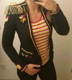 a woman taking a selfie in front of a mirror wearing a jacket and striped shirt