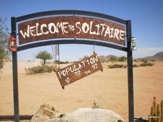 a sign that says welcome to solitaire in front of a desert area with cacti