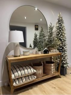 a mirror and some christmas trees on a shelf in front of a wall with lights