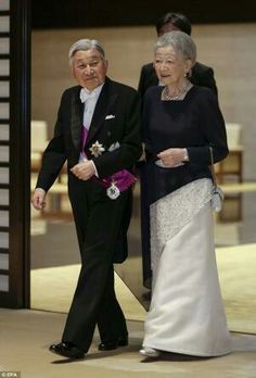 an older man and woman are walking down the aisle in formal attire, dressed in black