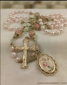 a rosary with an ornate cross and pink flowers on it, sitting on a table