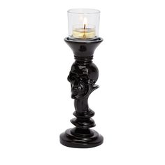 a black candle holder with a skull head on the front and one candle in the middle