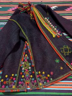 three pieces of cloth are laying on a tablecloth with colorful designs and beads around the edges