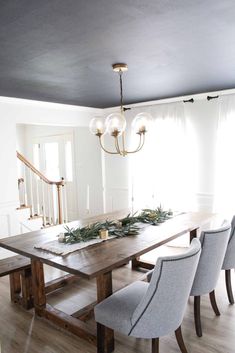 the dining room table is set with chairs and greenery on it, along with candles