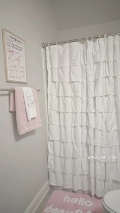 a bathroom with a white shower curtain and pink rug