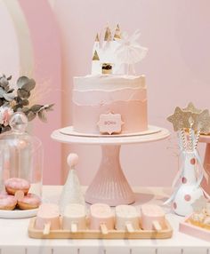 a table topped with pink cakes and cupcakes