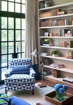 a living room filled with furniture and bookshelves next to a large open window