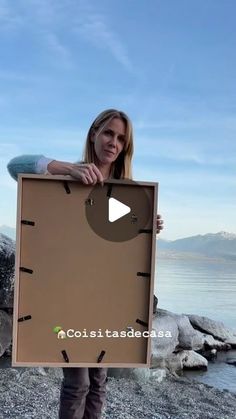 a woman is holding up a cardboard box with holes in it while standing on the beach