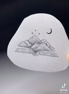 an open book with mountains in the background and a crescent on it's cover