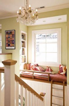 a living room with a window seat and a chandelier hanging from the ceiling