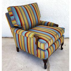 a colorful striped chair sitting in front of a white wall with no one around it