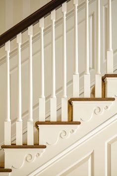 a white staircase with wooden handrails and rails