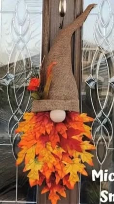 a scarecrow door hanger decorated with fall leaves and a burluck hat